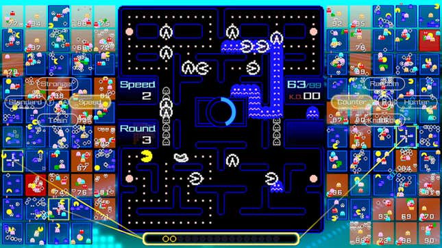 Various Pac-Men make their way around a giant maze board.