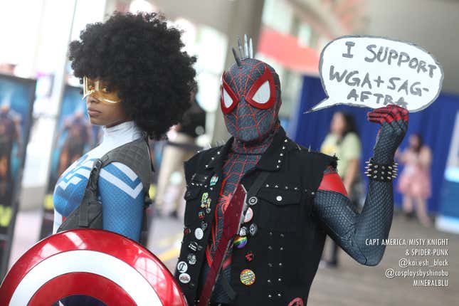 Misty Knight in her Captain America outfit and Spider-Punk, the latter of which is holding up a sign that reads "I support WGA+SAG-AFTRA,"